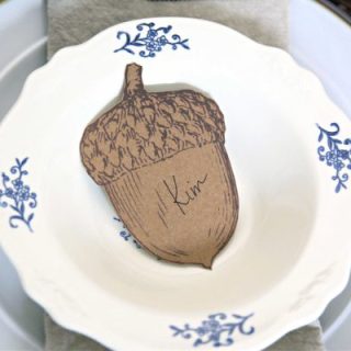 Brown paper acorn place card placed in a white bowl. Ideas for Thanksgiving Table Settings