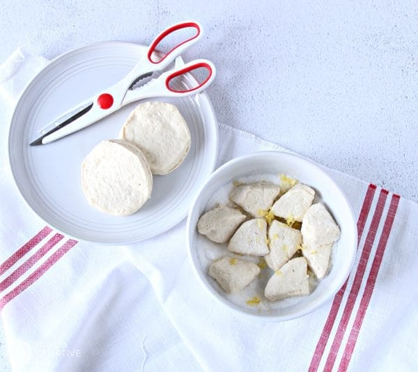 White bowl with sugar and cut and quartered biscuits.