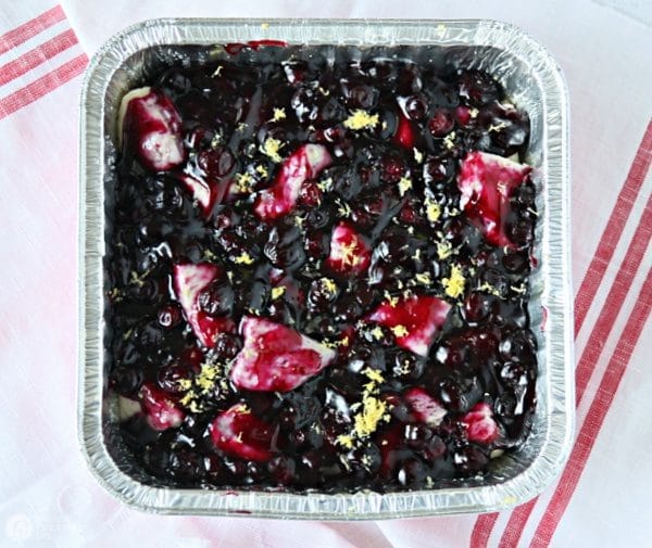 Baking dish with blueberry pie filling poured over quartered biscuits