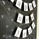 Printable Happy New Year Banner in black and white hung on a chalk board