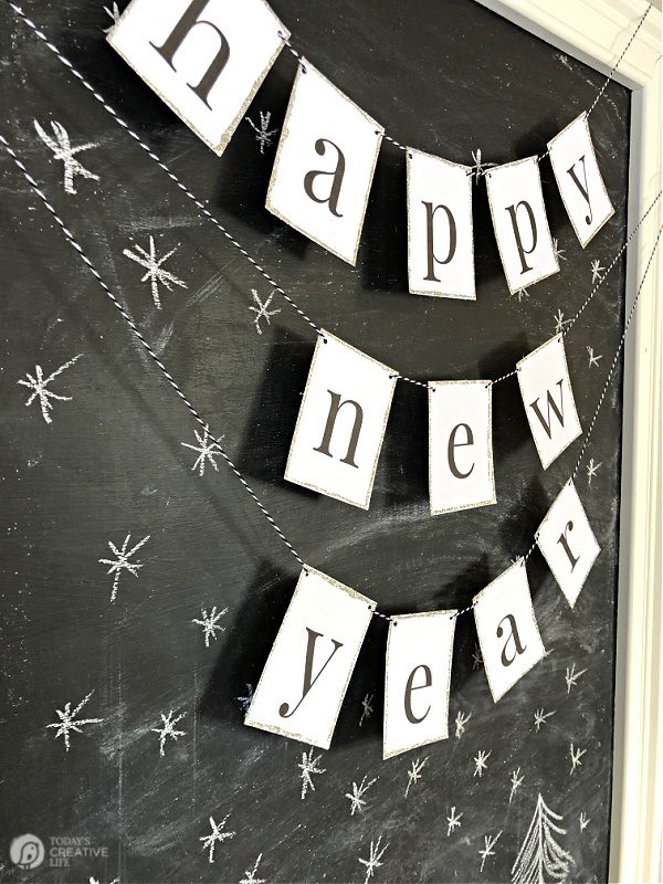 Printable Happy New Year Banner in black and white hung on a chalk board