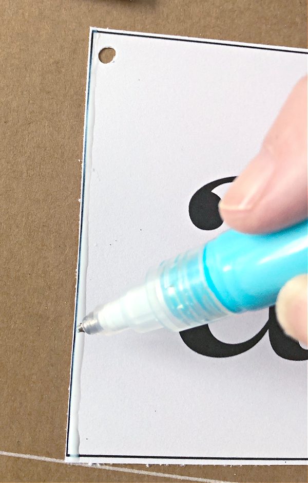 Applying glue to the edge of each tag with a glue pen