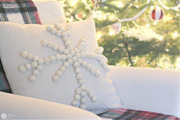 Cream colored diy snowflake pillow in chair next to Christmas Tree