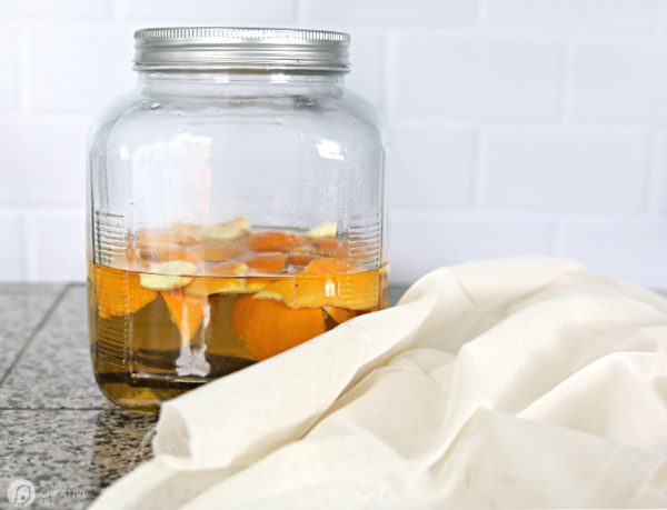 Jar filled with orange peels, vanilla beans and vodka with a cheesecloth.