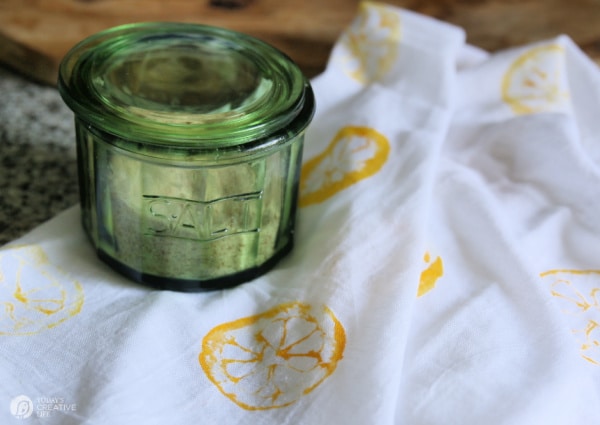 Green salt jar sitting on DIY Lemon Stamped Tea Towels