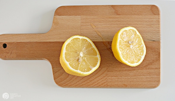Lemon sliced in two on a wood cutting board.