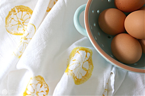 Bowl of brown eggs on white tea towel that is a diy lemon stamped tea towel.