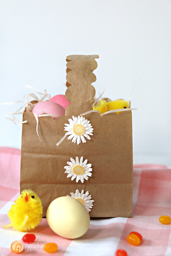 Brown paper Easter Basket made from a paper bag. Filled with easter grass and eggs. Daisy stickers on the front.