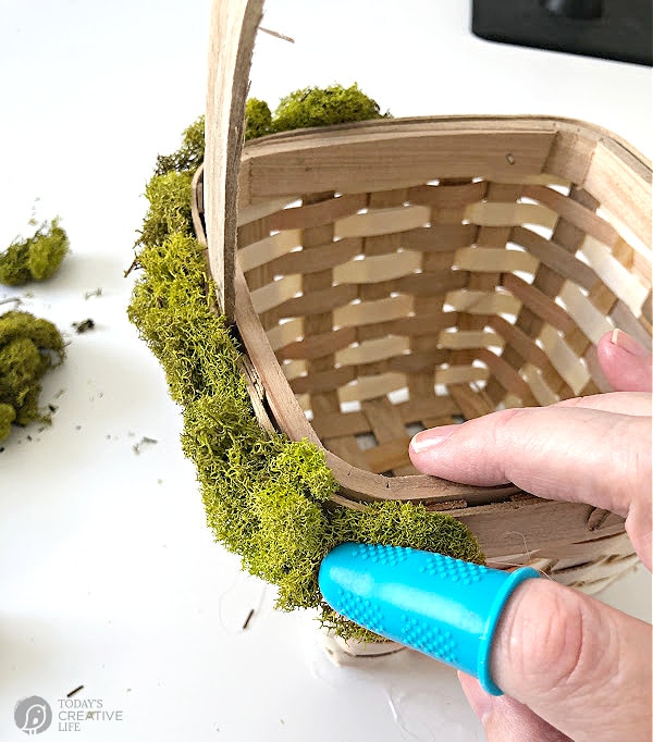 Silicone covered finger applying moss to a basket with hot glue. Easter Basket Idea