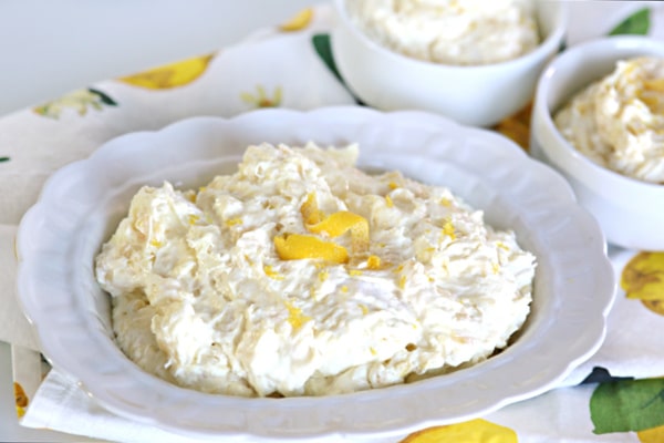 White bowl with Lemon Pineapple Fluff Dessert inside. Lemon Twist as garnish