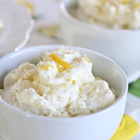 Small white bowl with Pineapple Lemon Fluff dessert and a lemon twist for garnish