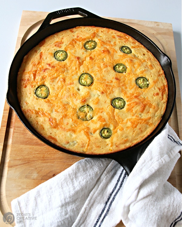 Corn Jalapeno Bread in a cast iron skillet. Golden brown with sliced jalapenos on top
