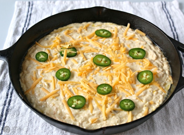 cast iron skillet with jalapeno cornbread with sliced jalapenos on top.