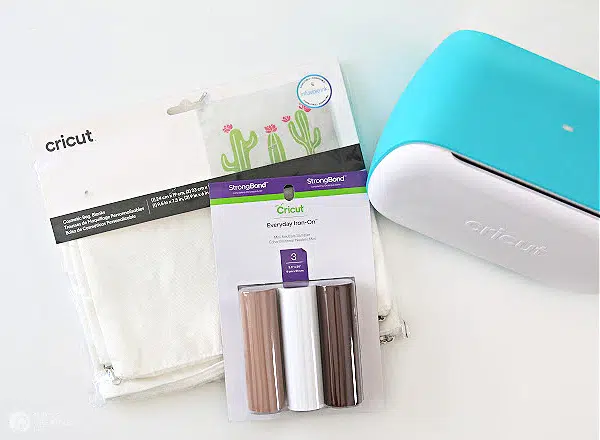 Cricut Joy cutting machine with supplies for making iron-on design on canvas pouch.