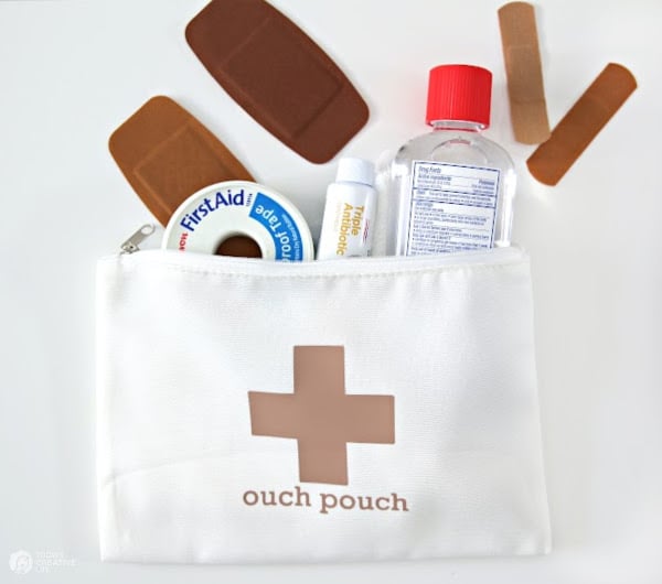 White cosmetic bag named Ouch Pouch filled with first aid supplies. What is a Cricut?