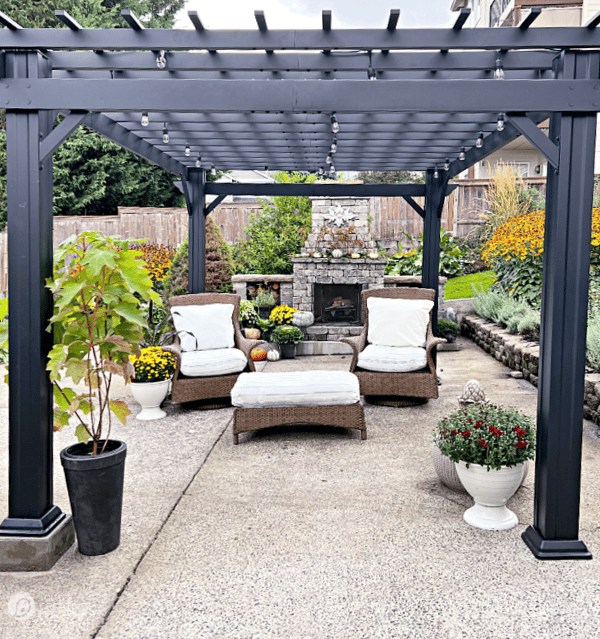 Outdoor setting under a black pergola with patio furniture.
