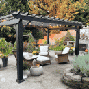 Black pergola with lights and light colored patio furniture.