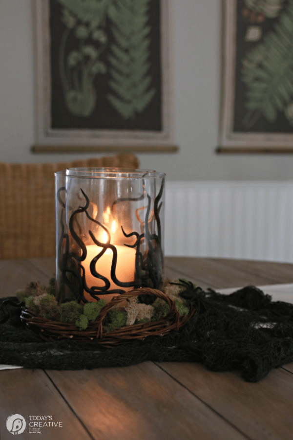 Glass vase with black plastic snakes with a lit candle for a DIY Halloween Centerpiece