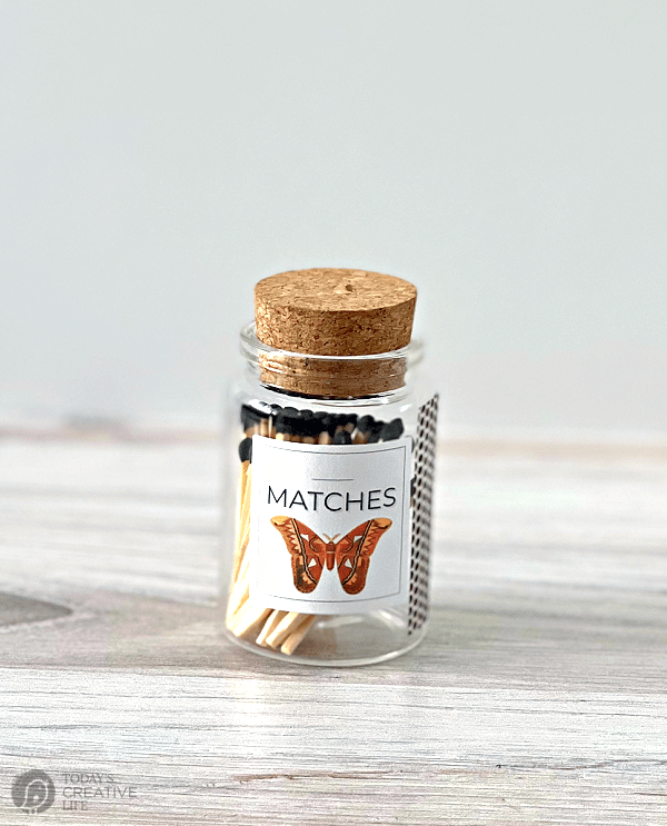 small glass bottle with a butterfly label filled with wood matches.