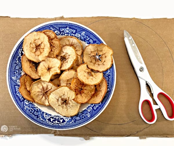 Dried Apple Slices in a blue bowl on a piece of cardboard.