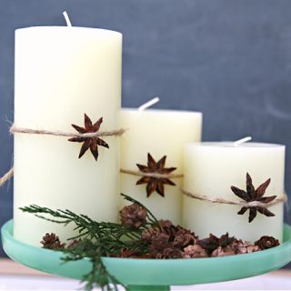 Three white candles on a green cake plate. Star Anise tied around candle for decor. Decorating for Christmas with Candles.