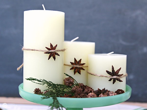 Three white candles on a green cake plate. Star Anise tied around candle for decor. Decorating for Christmas with Candles.