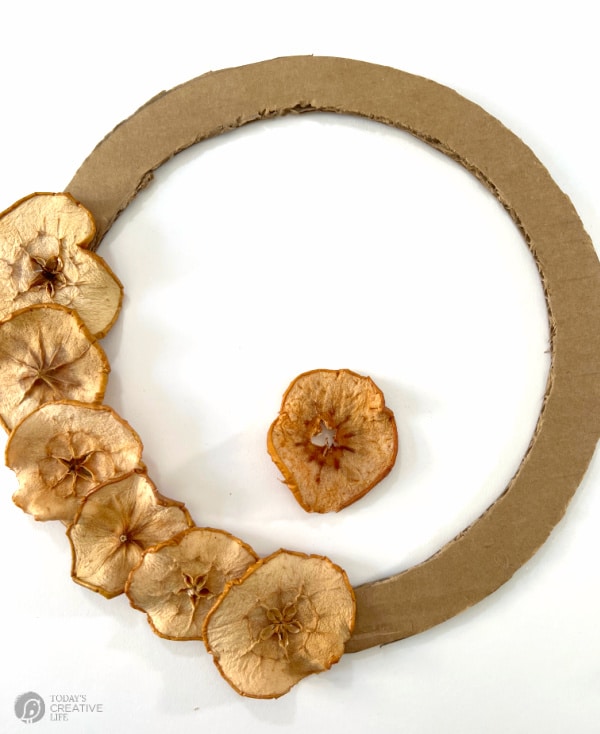 Dried Apple Slice Wreath gluing slices around wreath form.