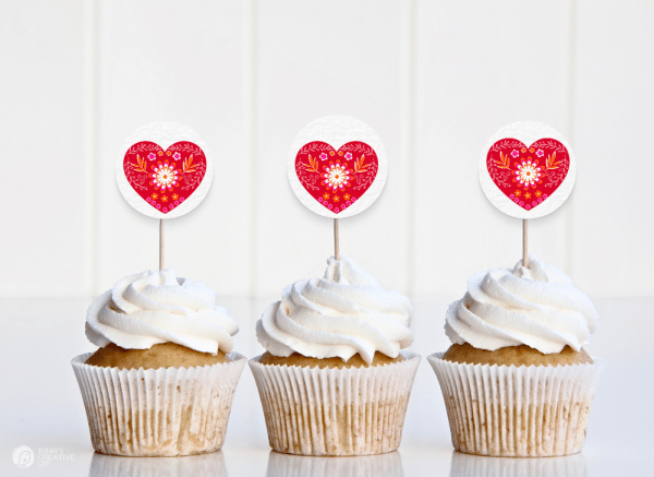 3 cupcakes with diy cupcake toppers with a red nordic design heart.