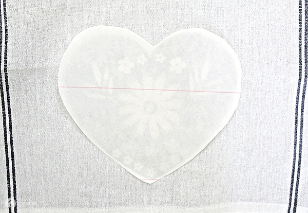Iron-on transfer paper with heart graphic laying face down for iroining.