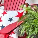 White pillow with red and blue stars setting on a red outdoor chair.