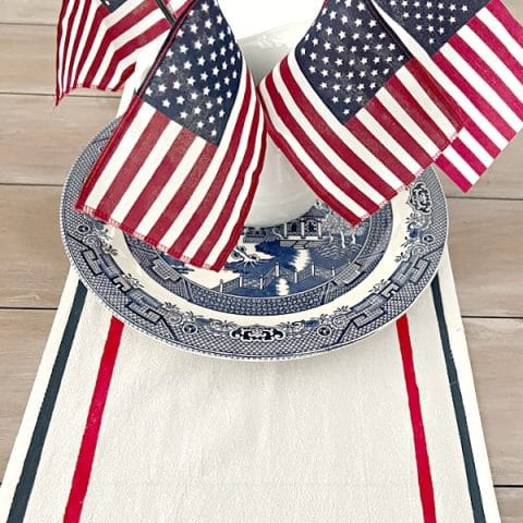 patriotic table runner with red and blue stripes on a table that has a bouquet of small American flags