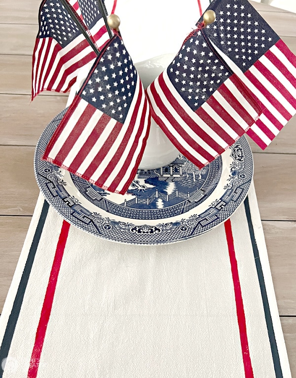 patriotic table runner with red and blue stripes on a table that has a bouquet of small American flags