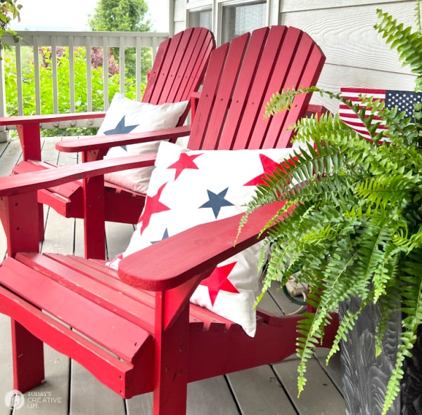 Patriotic Decorating Ideas with a white pillow with blue and red stars. Pillows on a red outdoor chair.
