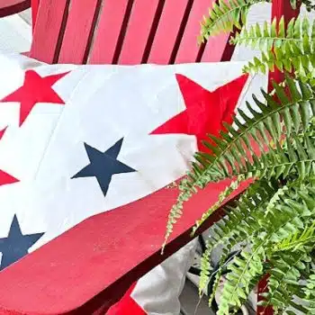 White pillow with red and blue stars setting on a red outdoor chair.