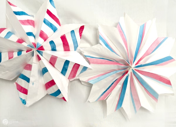 2 white paper stars with red and blue watercolor painted stripes.