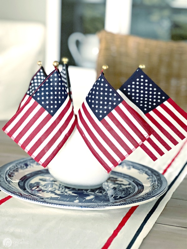 a bouquet of American Flags on a table runner with red and blue stripes. Patriotic Table Runner for home decor.