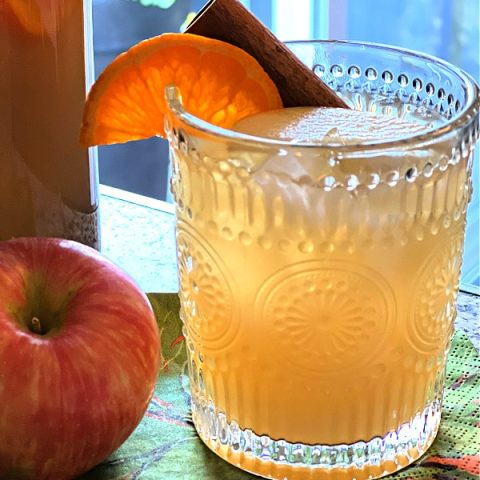 glass of apple cider sangria, garnished with an orange slice and cinnamon stick