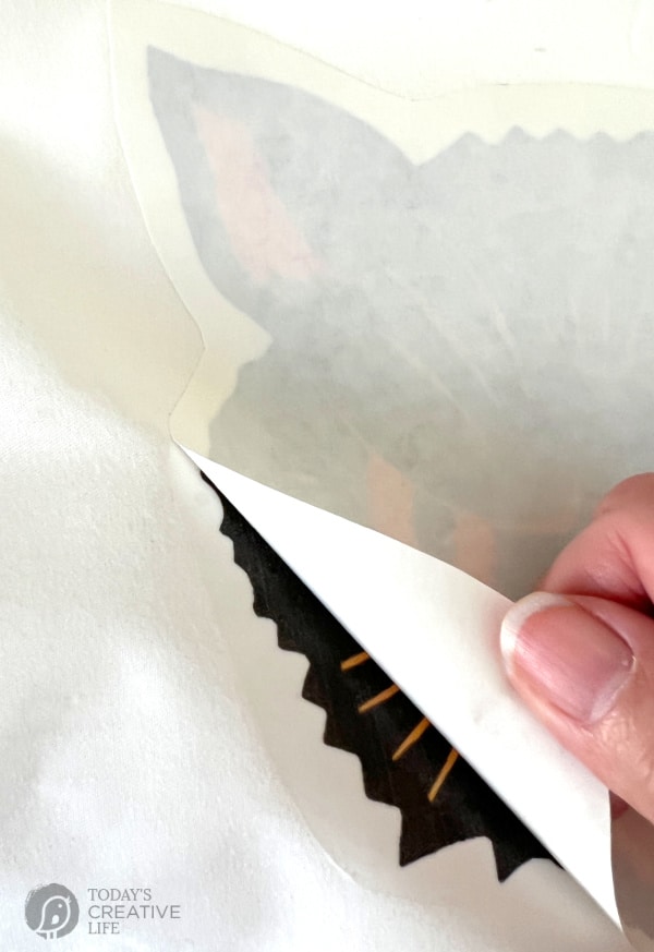 Peeling away iron-on transfer paper for making Halloween pillow covers
