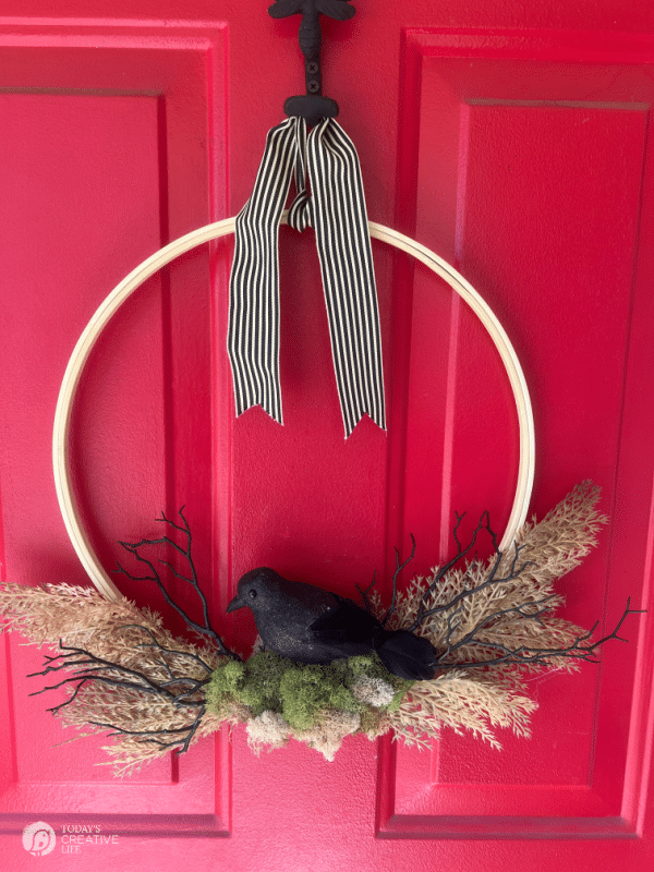 Red door with a Halloween Wreath that looks like a crows nest. Crafts for Halloween