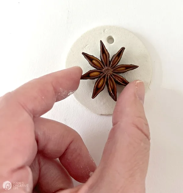 Placing a star anise seed into a white round piece of clay.