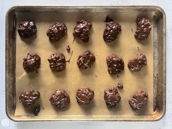 Slow cooker peanut clusters recipe - chocolate clusters scooped onto a baking sheet. 