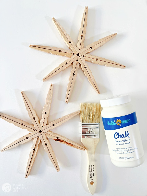 Two wood snowflakes with paint supplies.