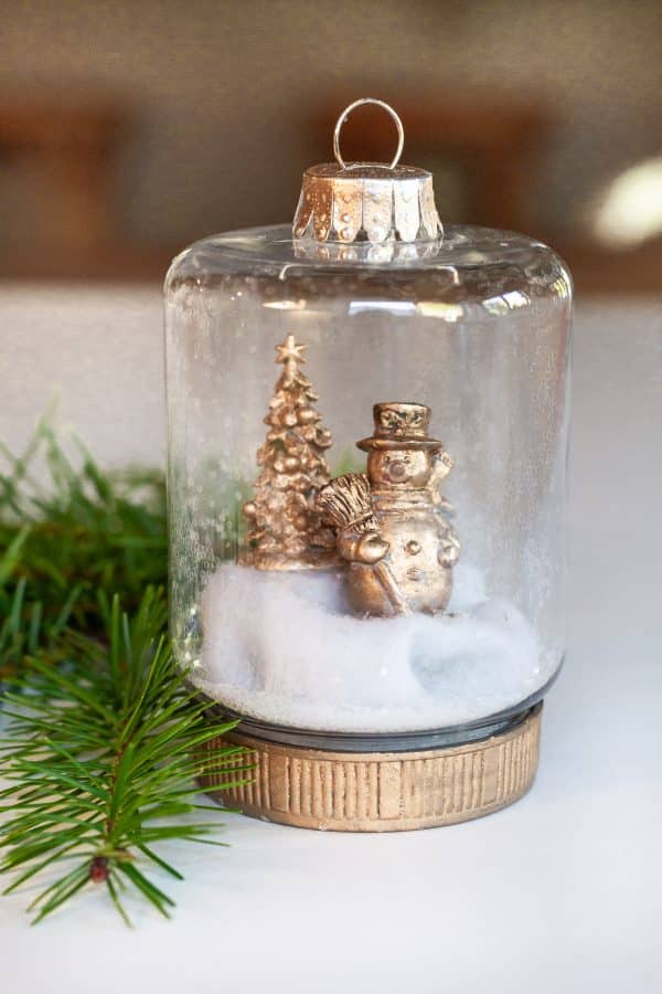 Homemade Christmas ornament with a gold snowman and tree inside. 