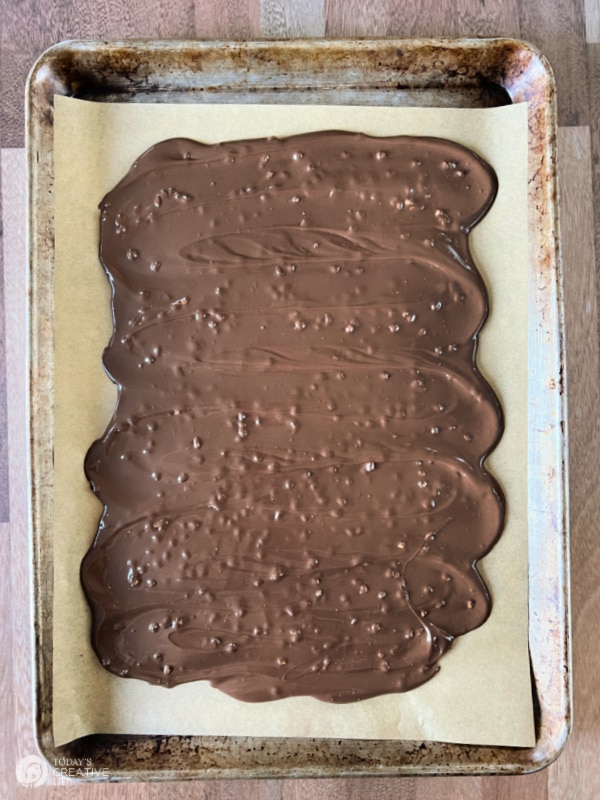 Melted chocolate spread onto a baking sheet for making a candy bark recipe.