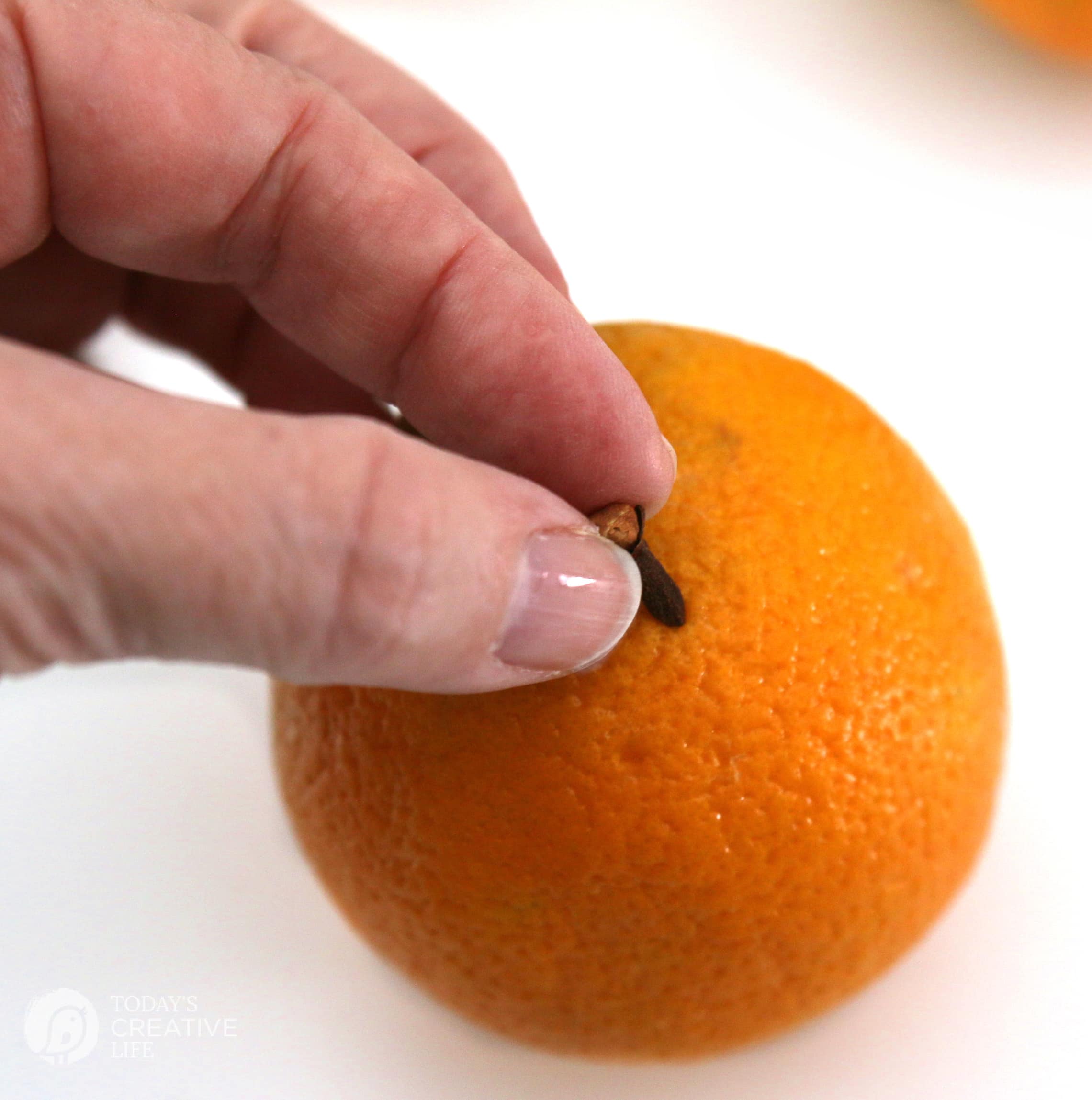 poking a clove into an orange for making orange and clove pomanders