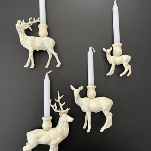Four white painted plastic deer that have been made into DIY Reindeer candle holders.