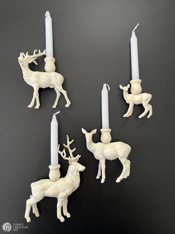 Four white painted plastic deer that have been made into DIY Reindeer candle holders.