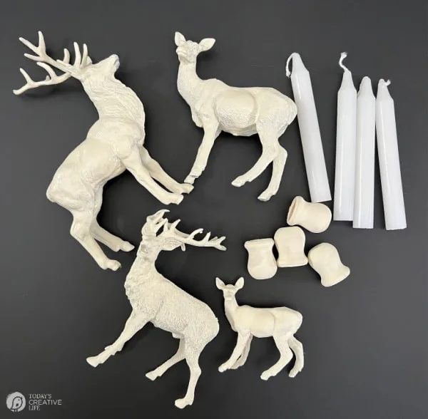 Spray painted white plastic deer with supplies to make candle holders.