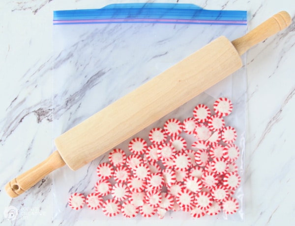 round peppermint candies in a plastic bag with a rolling pin. 