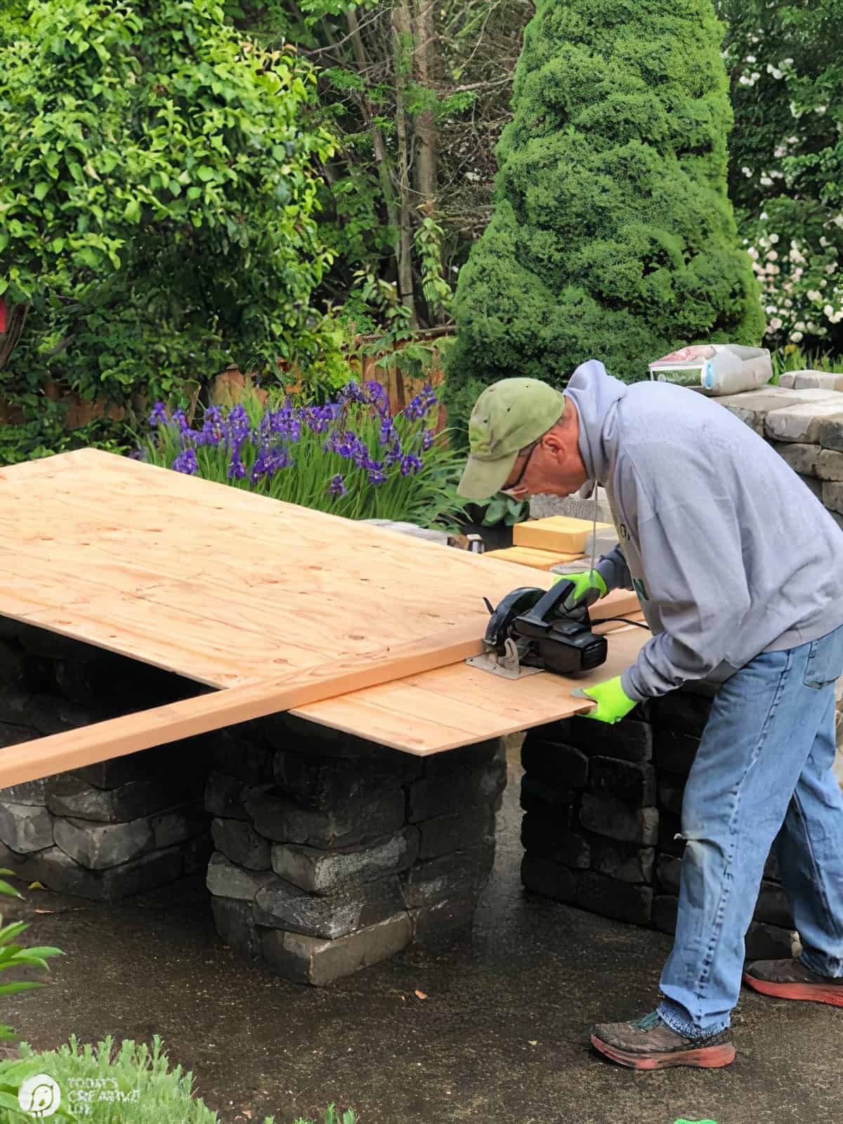 Man using a skill saw on a large piece of plywood